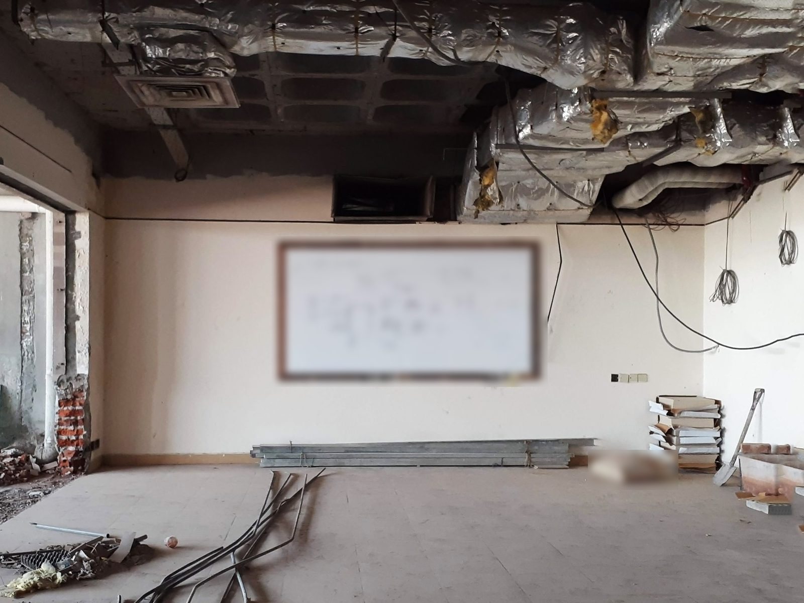 Gutted interior room with exposed ductwork, cables and a whiteboard